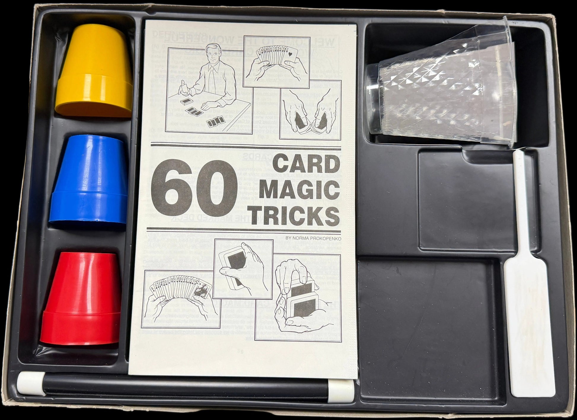 Card magic tricks set with cups and a knife on a table