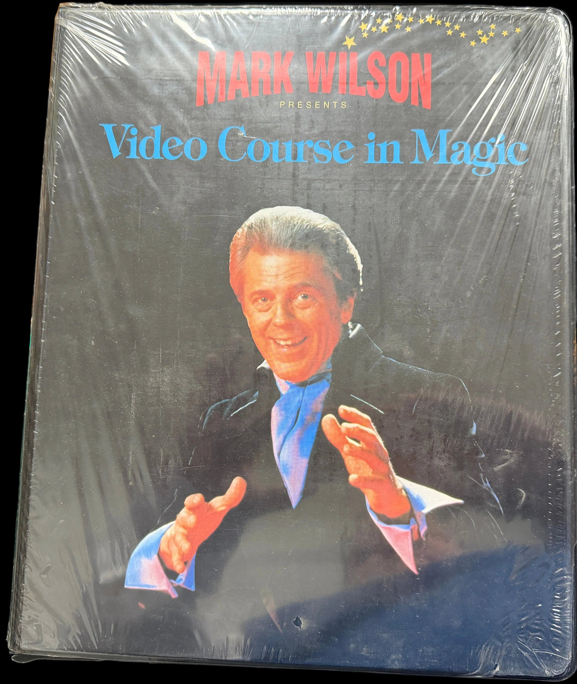 Packaged video course in magic with a person on the cover, sitting on a desk.