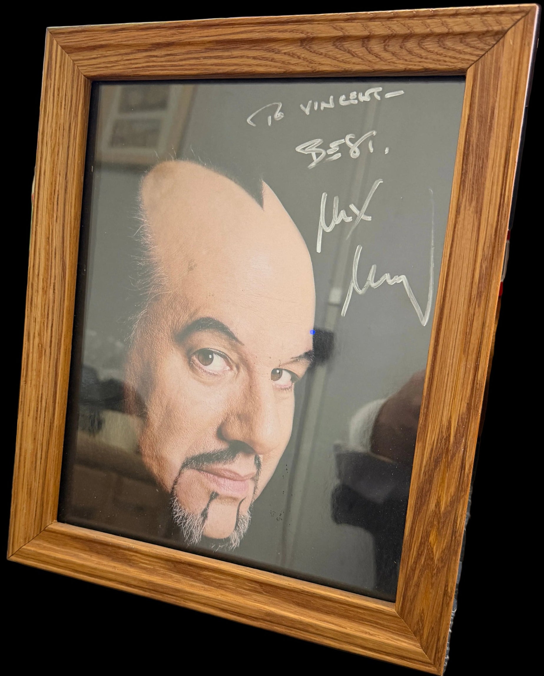 Framed portrait of a person with a signature above it on a cluttered desk.
