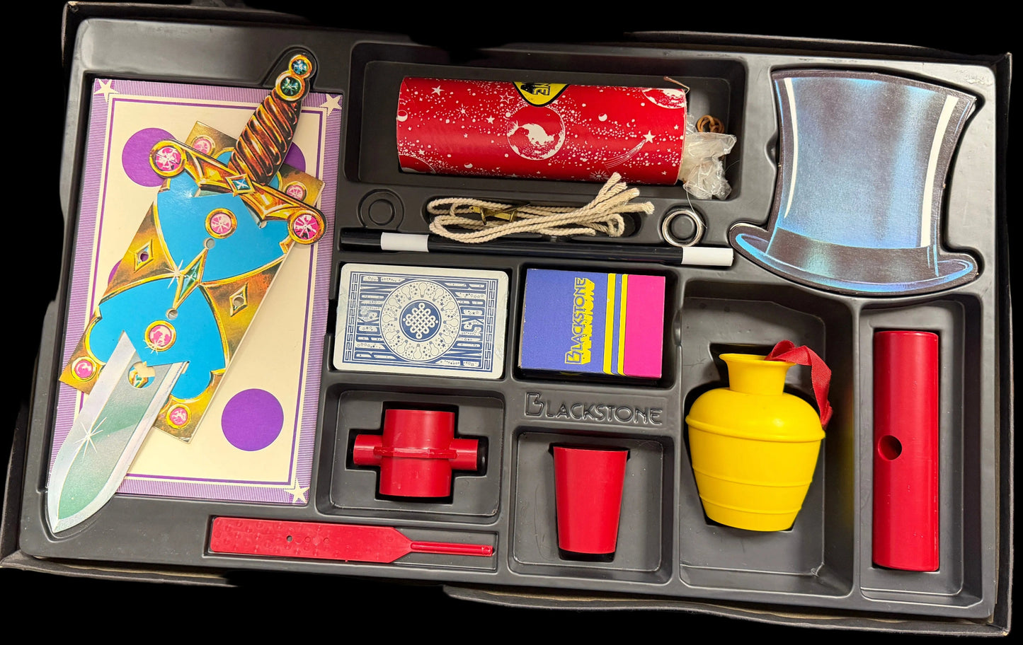 Collection of board game components in a black tray on a desk.