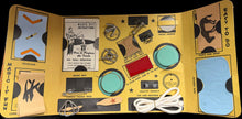Open toy kit with various components on a black background