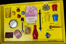 Yellow toy box with various toys and accessories on a dark surface