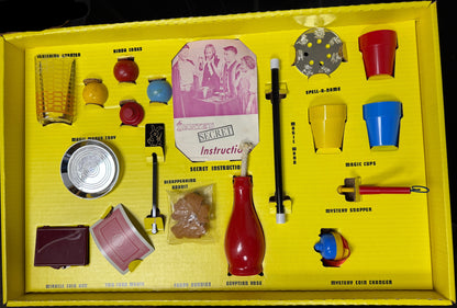 Yellow toy box with various toys and accessories on a dark surface