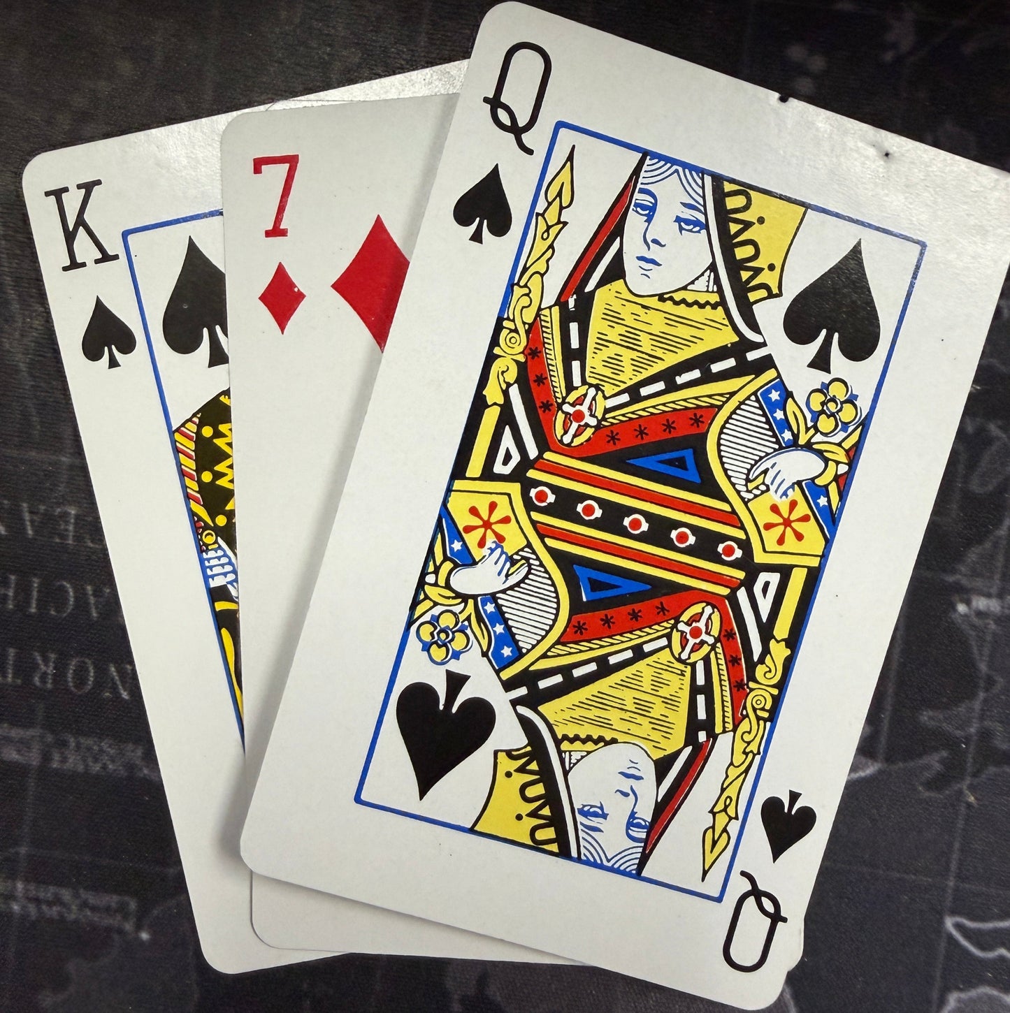 Playing cards with a focus on the Queen of Spades on a dark textured surface
