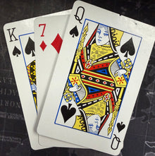 Playing cards with a focus on the Queen of Spades on a dark textured surface