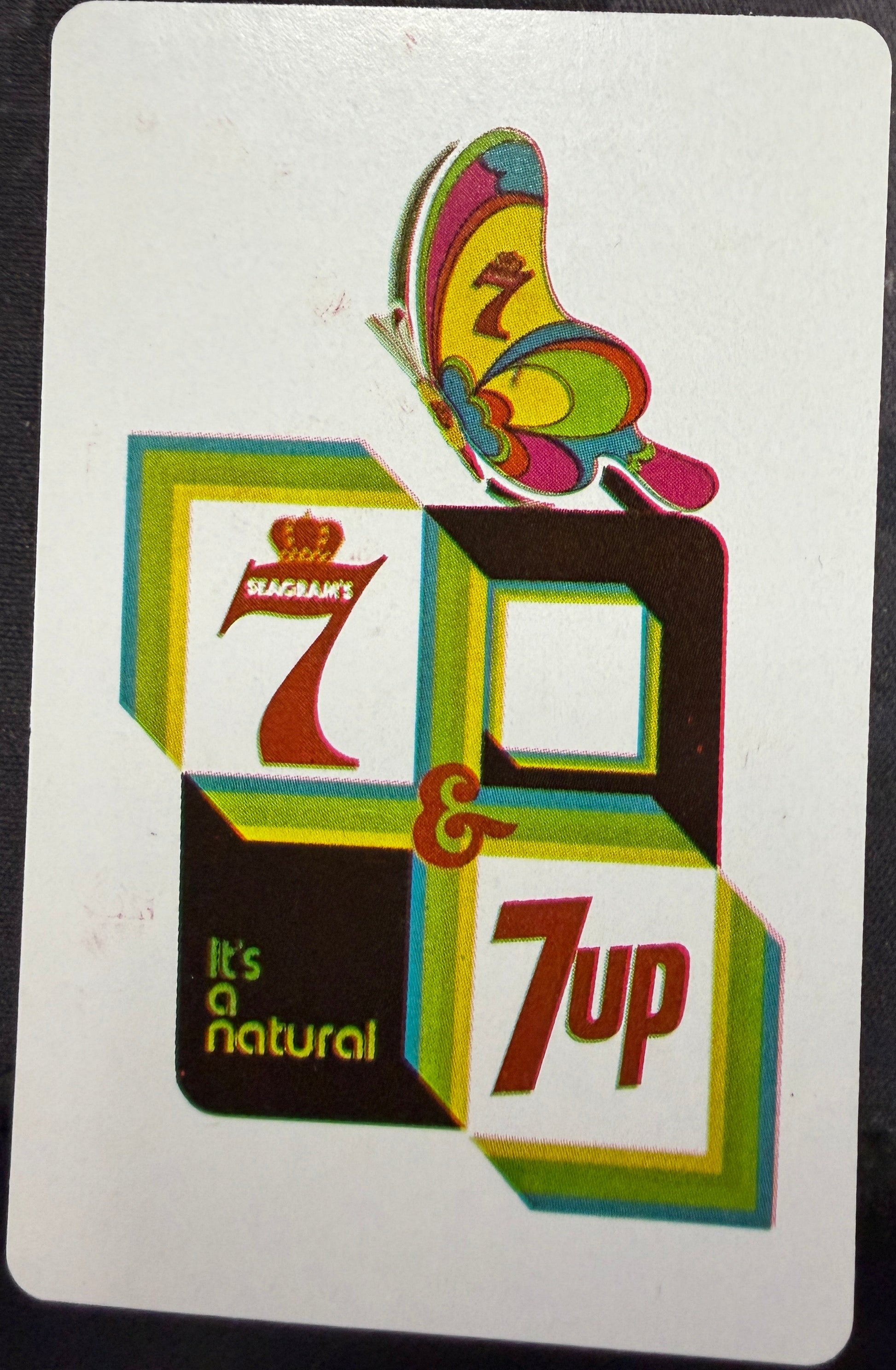 Playing card with 7up logo and butterfly design on a dark background