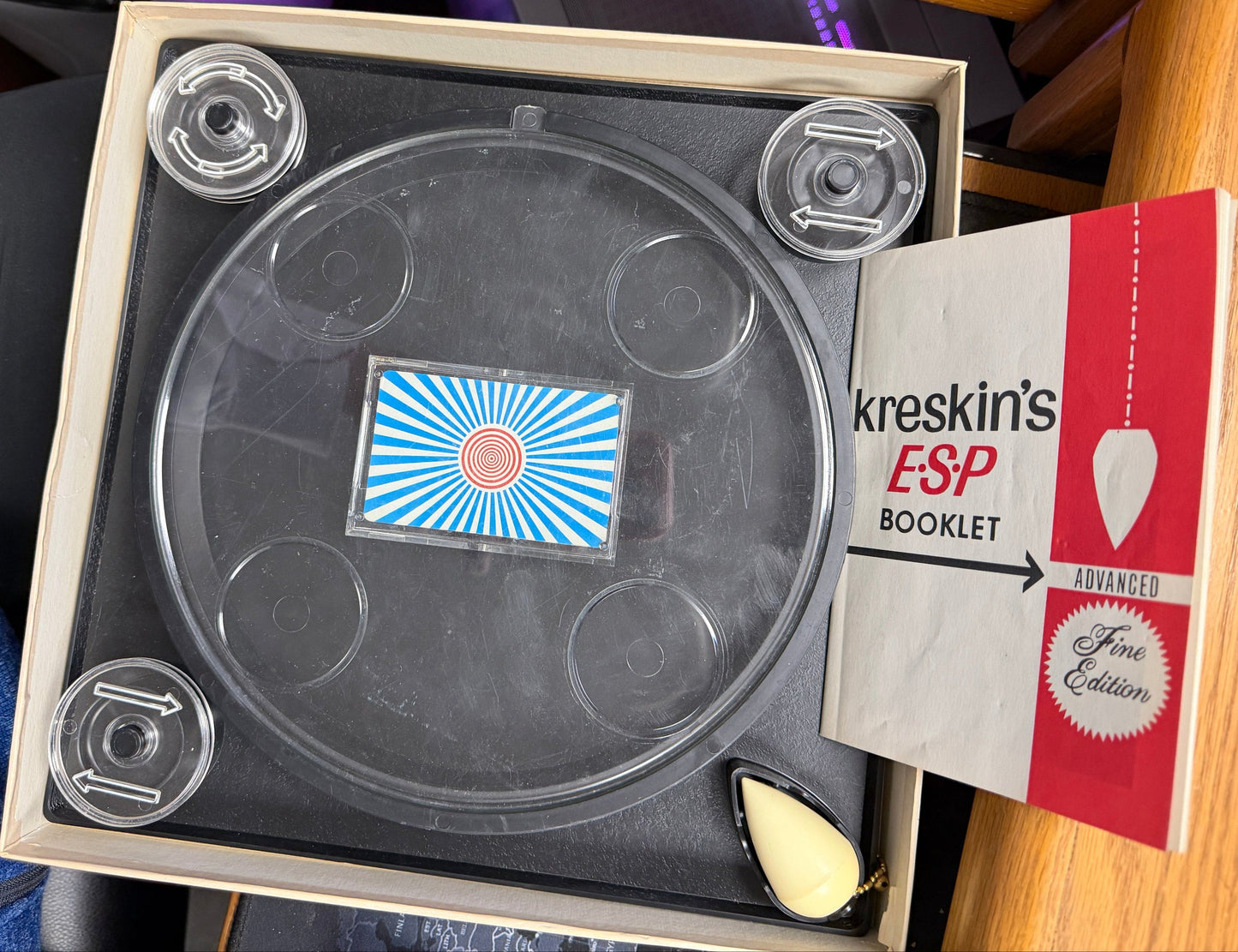 Circular object with a blue and white label inside a box, with a book titled 'Kerrison's' on the side.