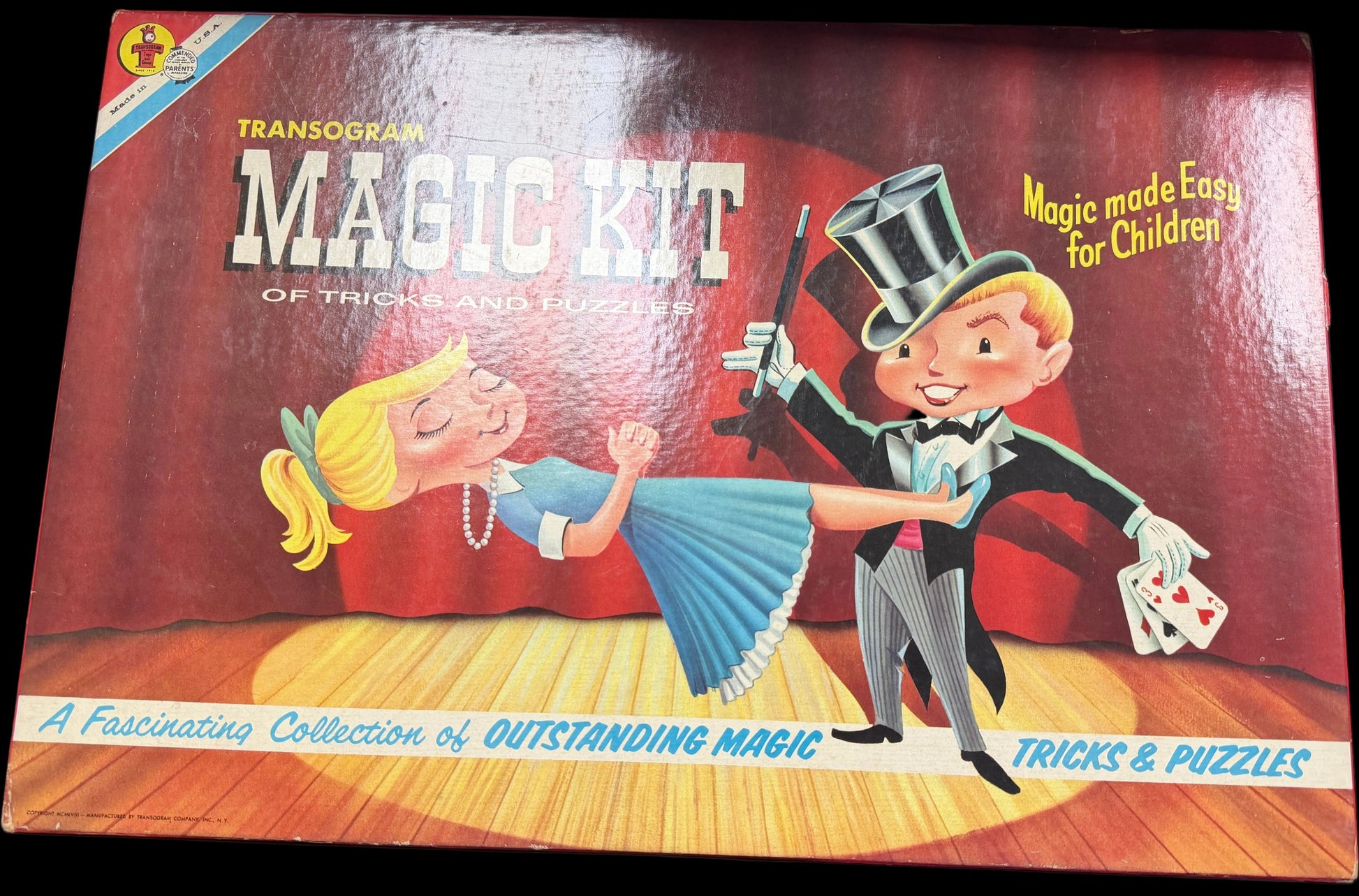 Vintage Transogram Magic Kit box with illustrations of a magician and a woman on a wooden stage.