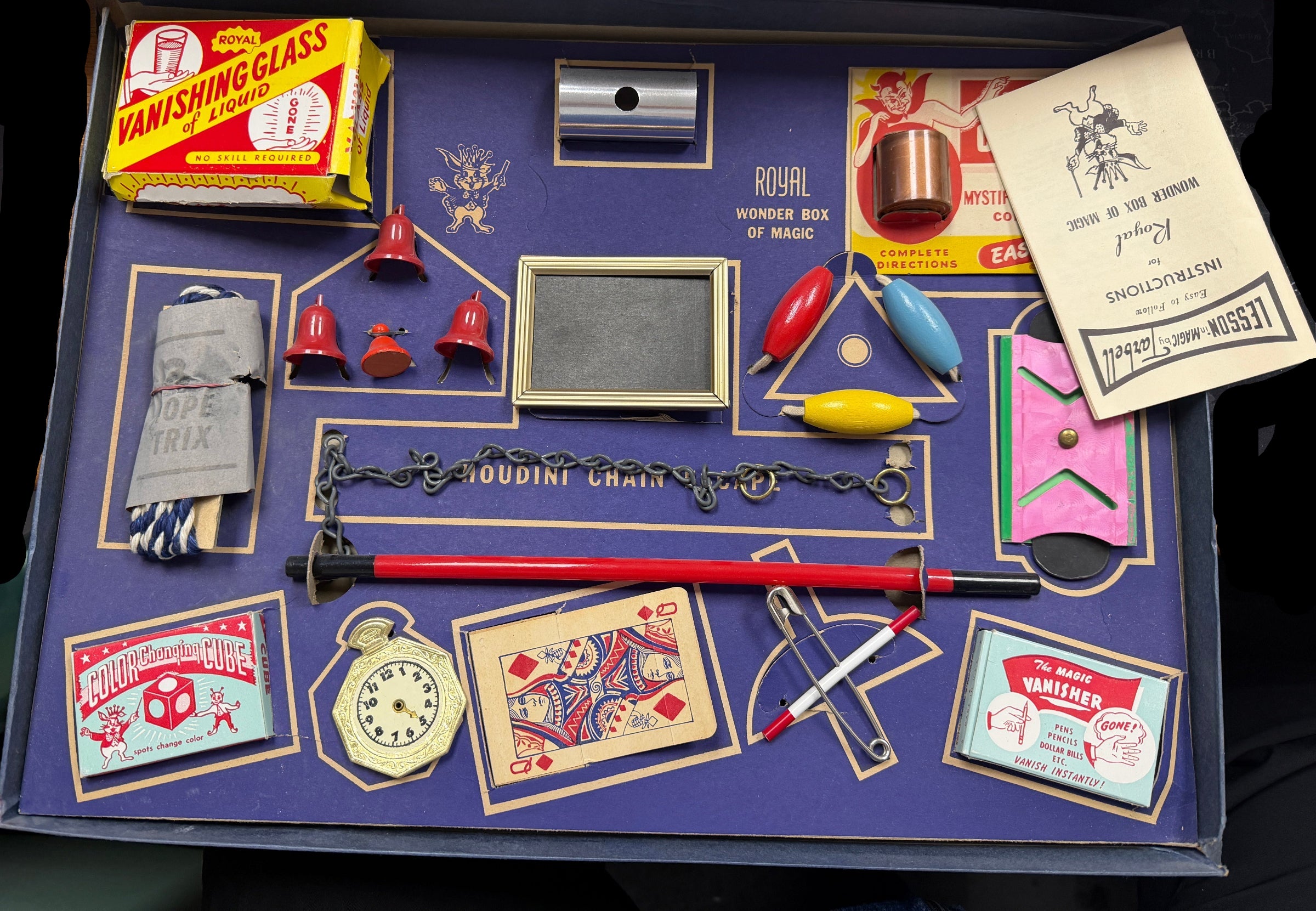 Collection of vintage magic tricks and props on a purple tray.