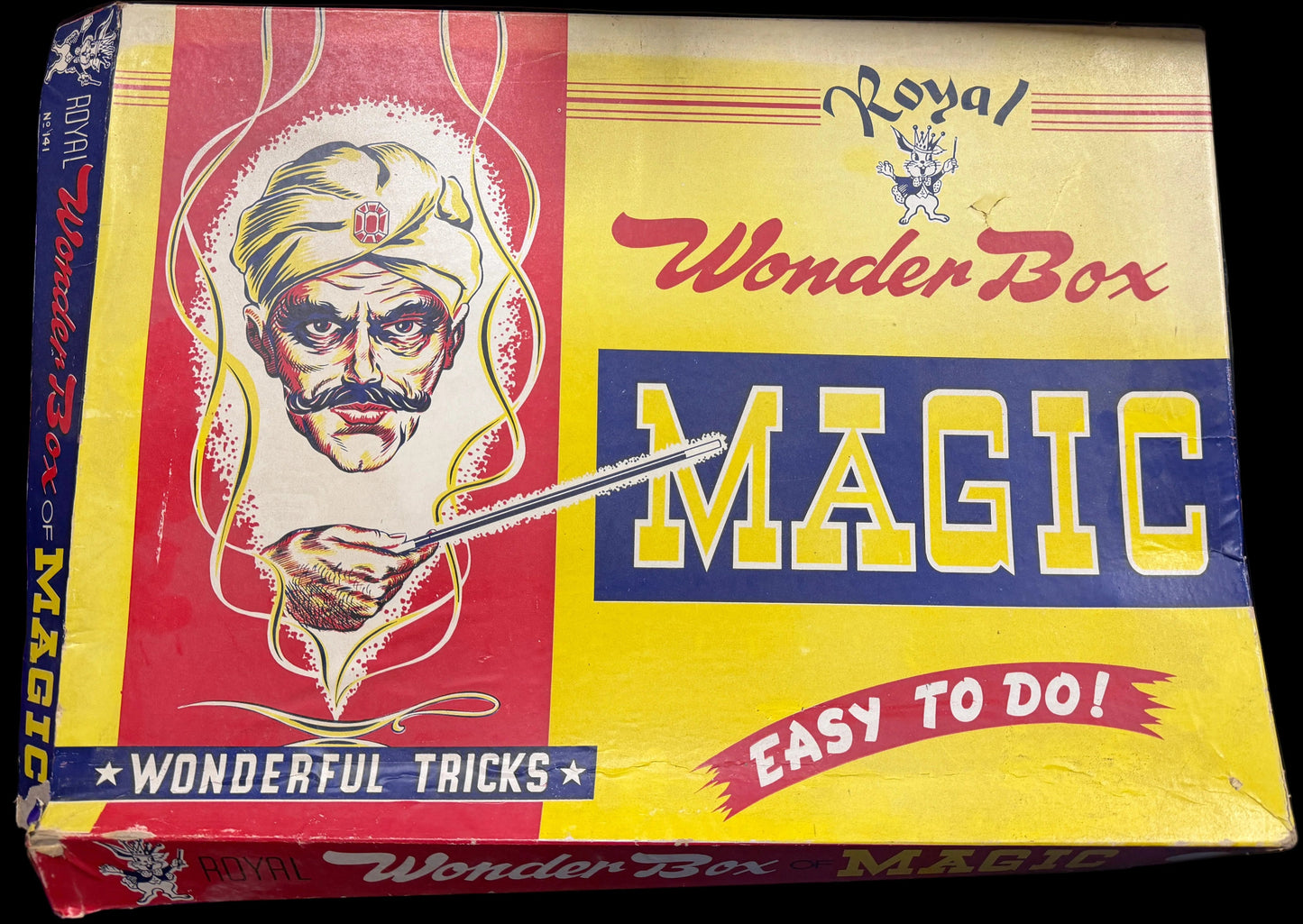 Vintage 'Royal Wonder Box Magic' box with colorful design on a wooden surface.