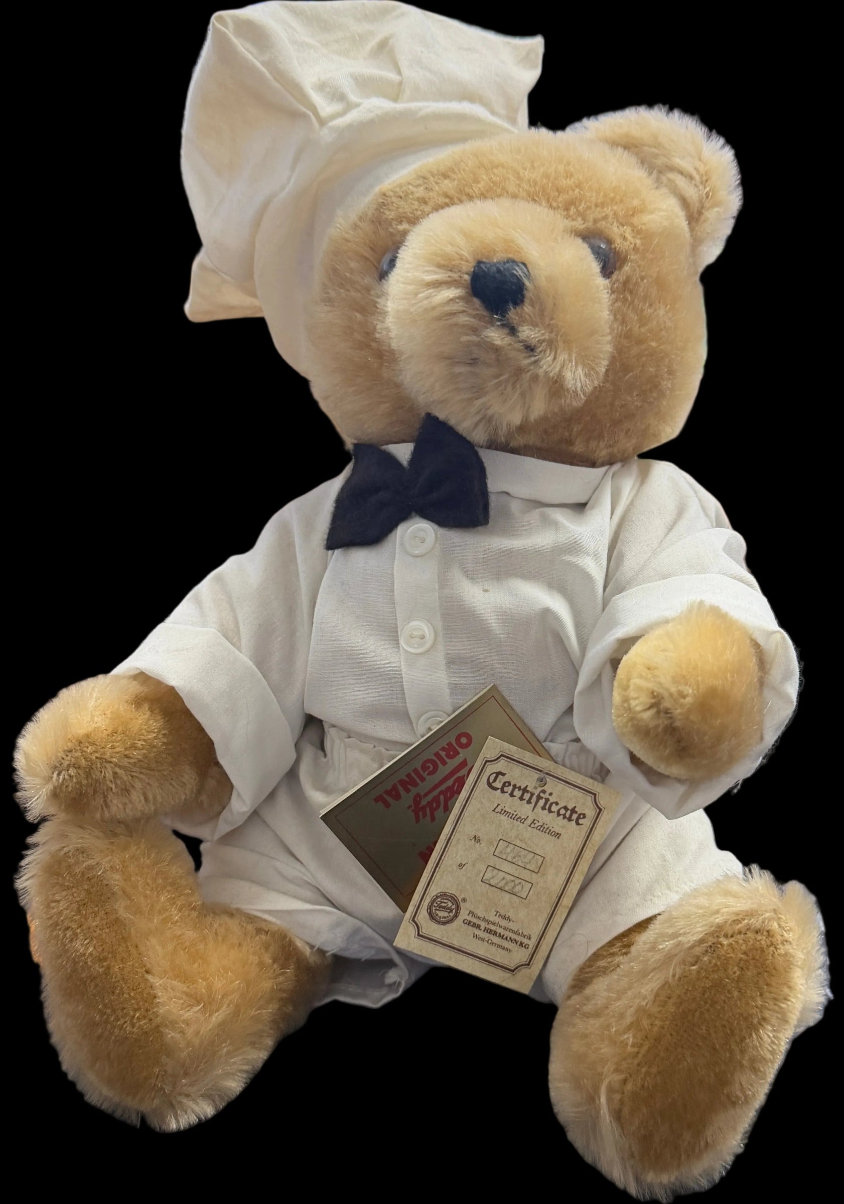 Teddy bear in a white coat with a tag on a desk in an office setting