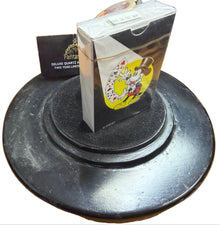 Small decorative item on a black stand with a wooden surface in the background