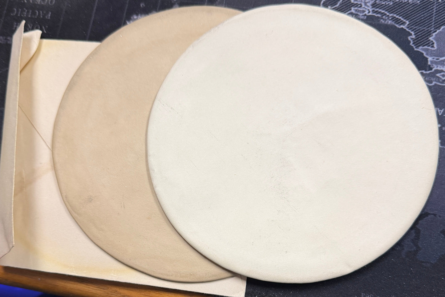 Two circular objects, one beige and one white, on a textured surface.