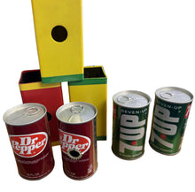 Collection of Dr Pepper and Seven-Up soda cans with a colorful box in the background.