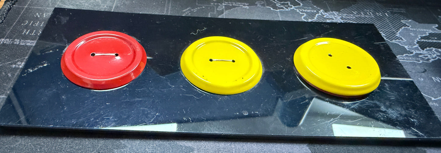 Three coffee cup lids, two yellow and one red, on a black surface.