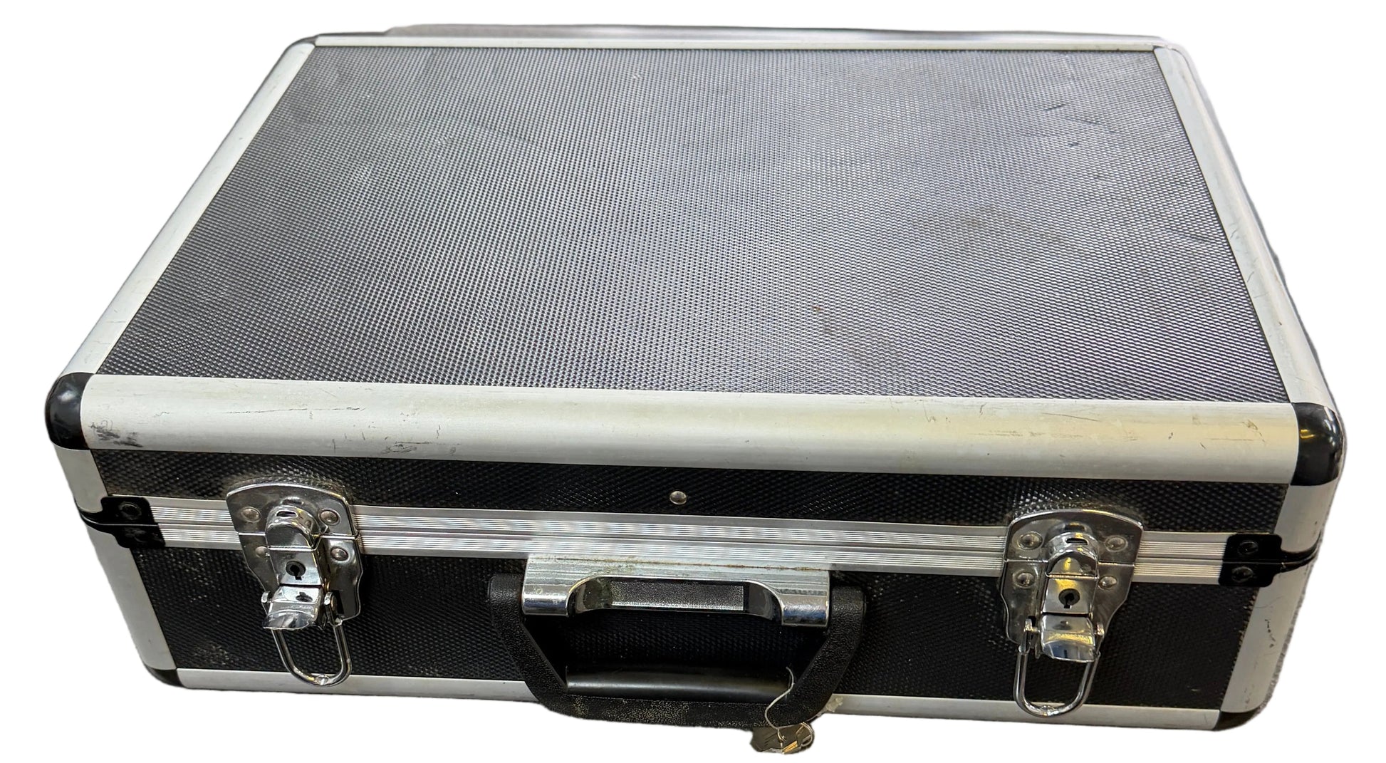 Black and silver briefcase on a gray surface with a window and chair in the background