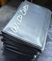 Stack of black cards with white text on a textured surface