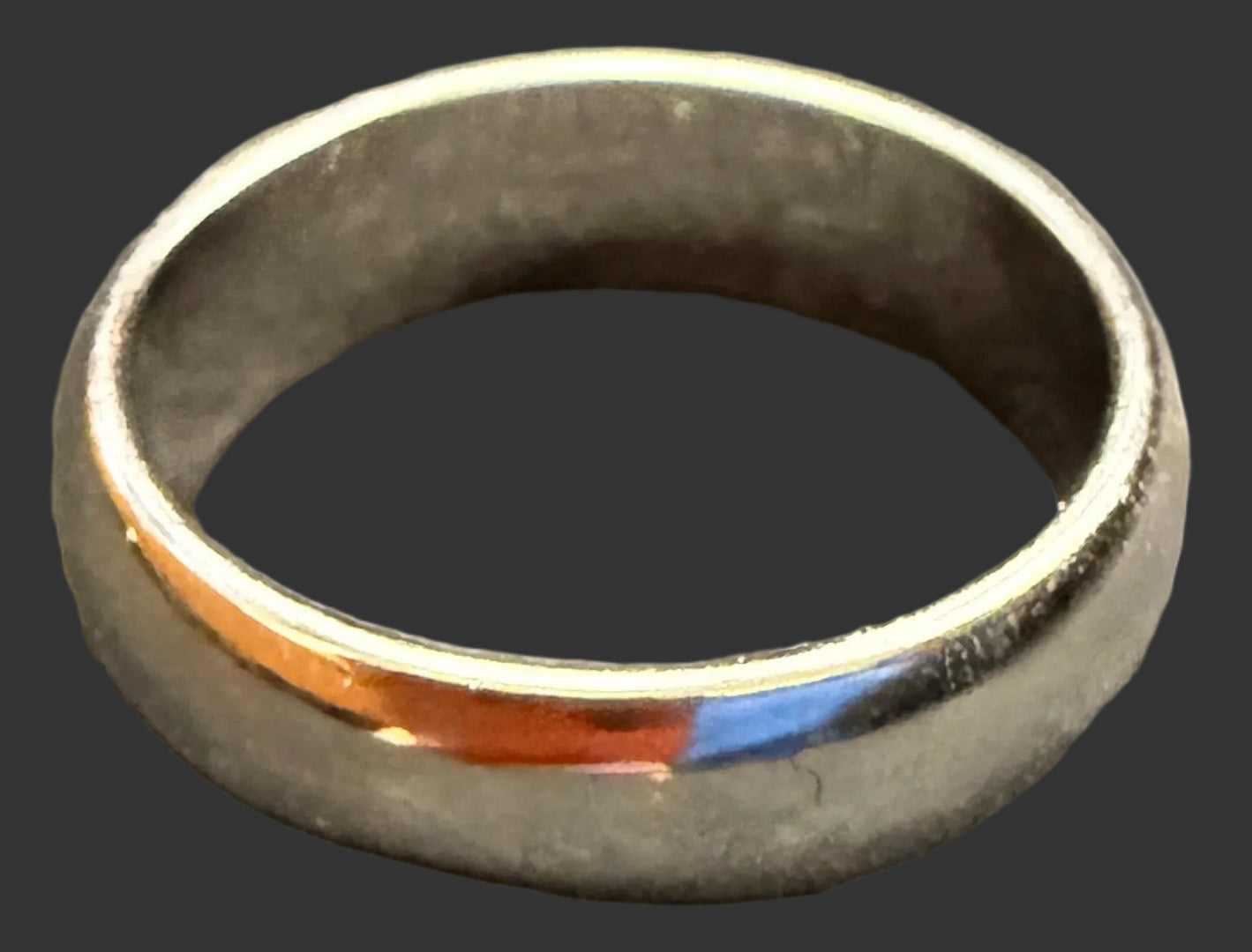 Silver ring with a colorful band on a textured gray surface