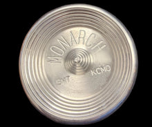 Metallic cylindrical object with 'KMC' branding on a world map background
