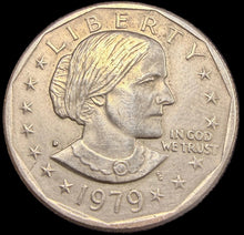 Silver coin with a face on it against a dark background