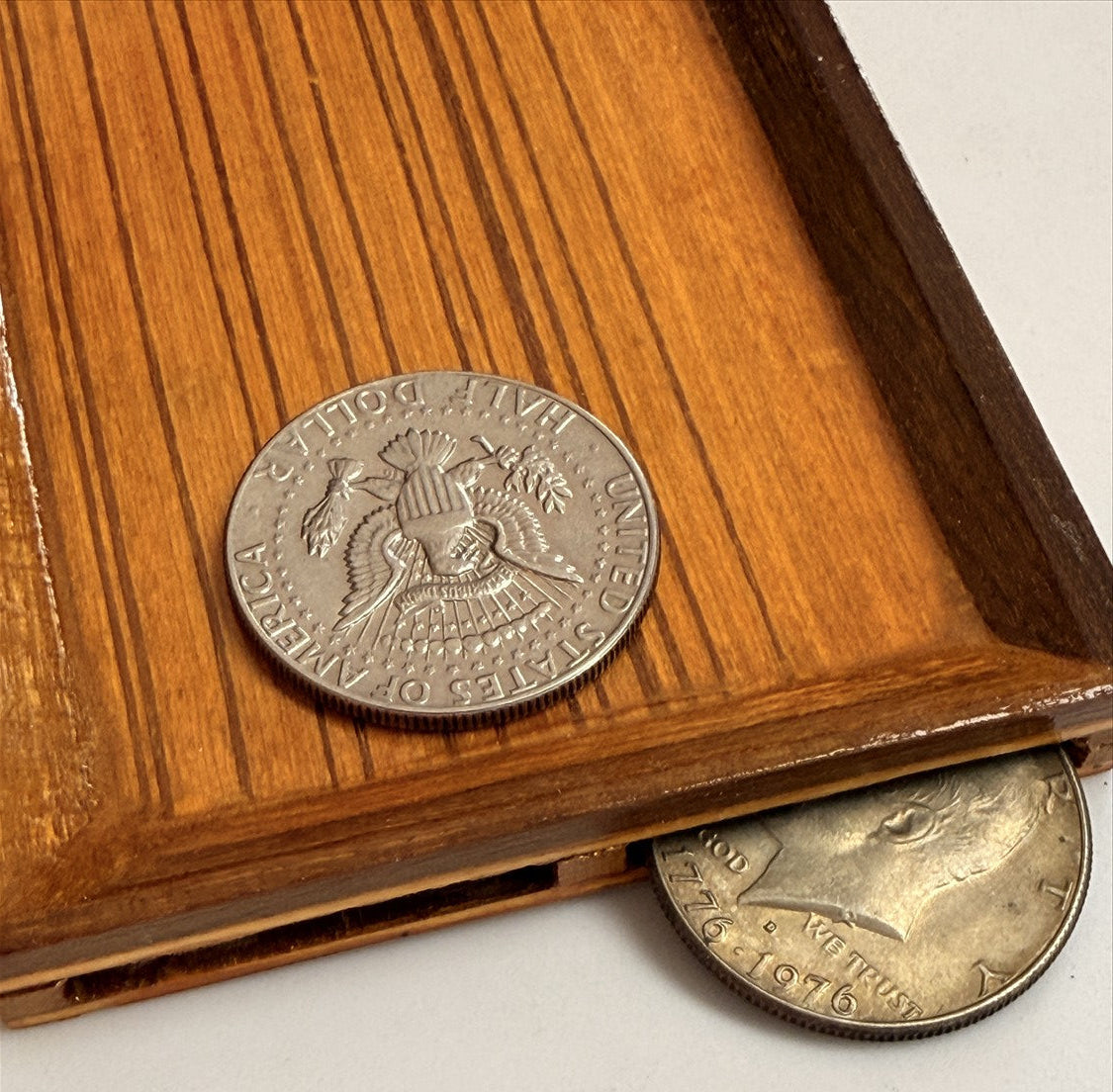 Two silver coins on a wooden surface with a white background