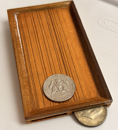 Wooden box with a silver coin on top, featuring a design of a person holding a sword.
