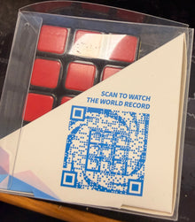 Makeup palette with red shades and a QR code on a card, on a dark surface.