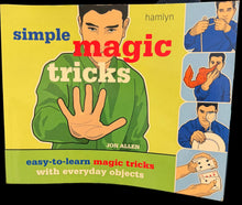 Book titled 'Simple Magic Tricks' on a desk with a computer screen in the background