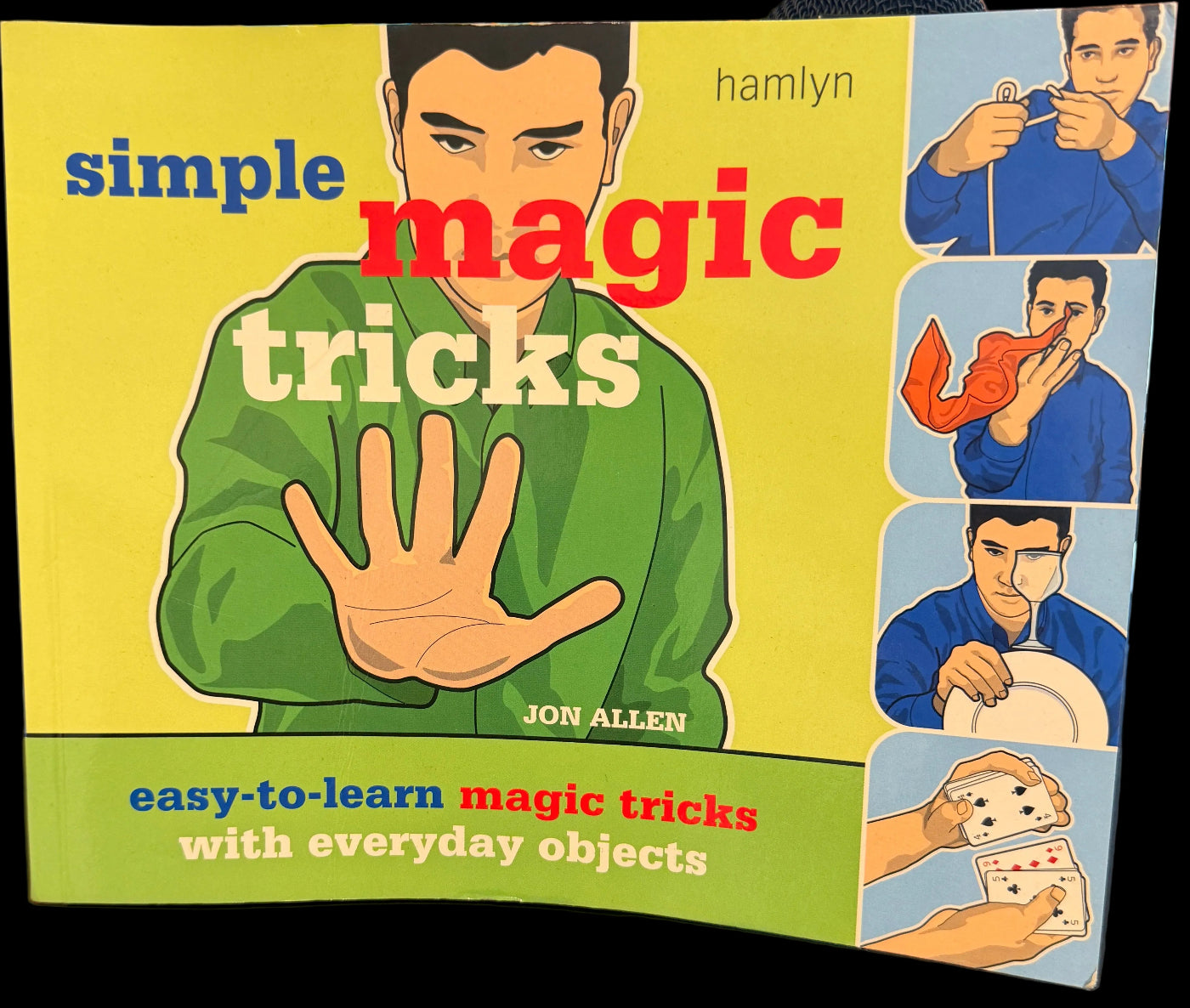 Book titled 'Simple Magic Tricks' on a desk with a computer screen in the background
