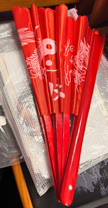 Red folding fans on a desk with a book and keyboard in the background