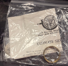 Gold ring in a clear plastic bag with a card on a dark surface
