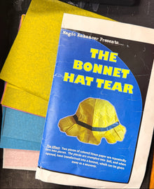 Book titled 'The Bonnet Hat Tear' with a yellow hat illustration on a dark surface
