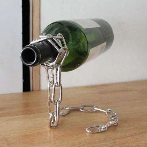 Metal bottle holder with chain holding a wine bottle on a wooden surface.