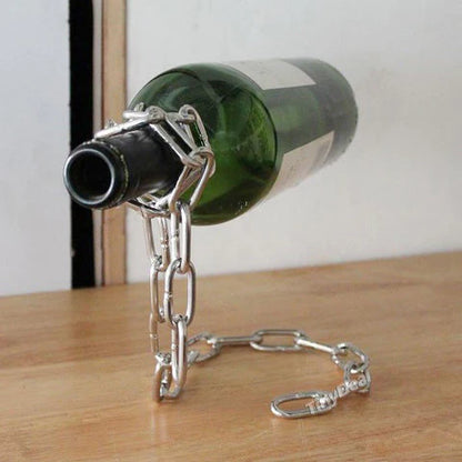 Metal bottle holder with chain holding a wine bottle on a wooden surface.