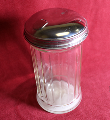 Glass container with silver lid on a red background, featuring MJM Magic branding.