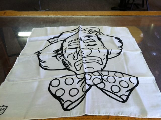 White fabric with black ink drawing of a character on a glass surface