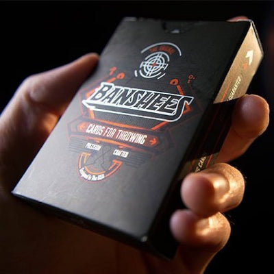 Hand holding a black card game box with 'Bamshad' branding on a dark background