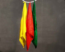Three colored flags (yellow, red, green) hanging against a dark background