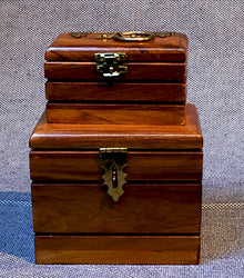 Two wooden boxes with brass locks on a textured gray background
