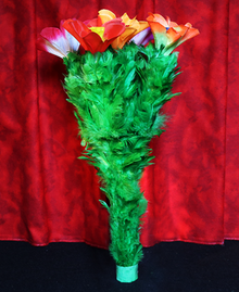 Bouquet of green feathers with red and white flowers against a red curtain background