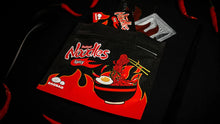 Spicy noodles packaging with red and black design on a dark background