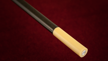 Cylindrical object with black top and beige bottom on a red background