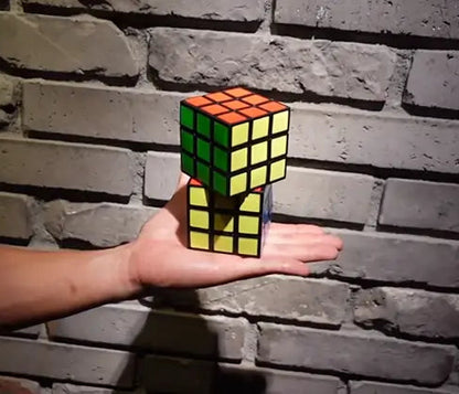 Hand holding a Rubik's Cube with a brick wall background