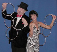 Man and woman in formal attire with hoop earring props against a blue background