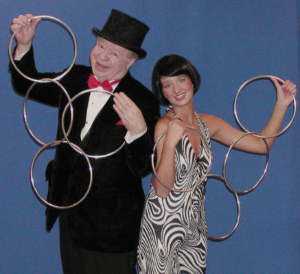Man and woman in formal attire with hoop earring props against a blue background