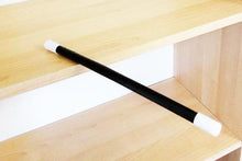Black rod with white ends on a wooden shelf