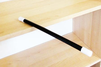 Black rod with white ends on a wooden shelf