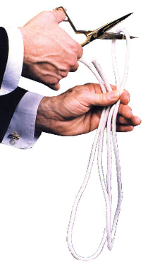 Person cutting a white cord with scissors on a white background