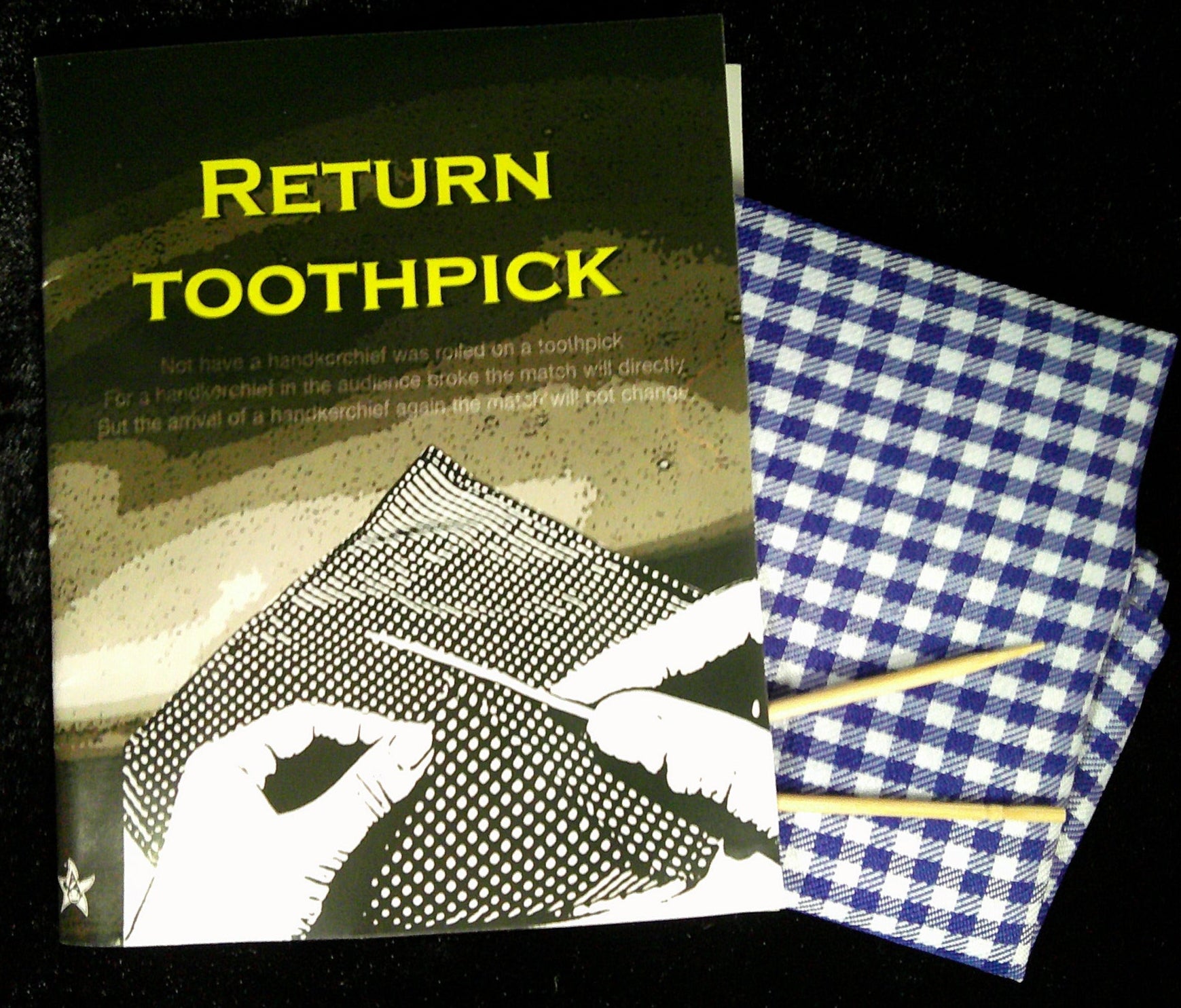 Booklet titled 'Return Toothpick' with toothpicks on a checkered cloth against a dark background