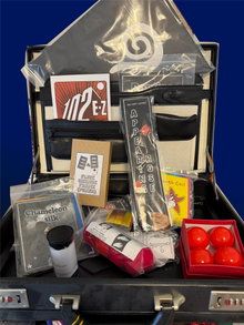 Collection of items including a suitcase, bags, and small containers on a blue background